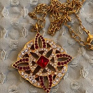 Necklace with a large pendant. Gold with red and white stones.